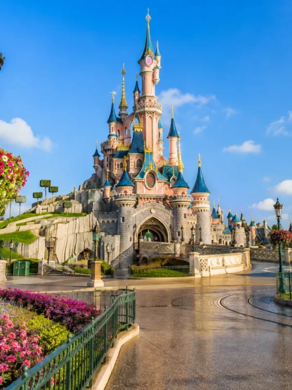 Disneyland Paris castle with fantasy gardens, clean pathways, blue sky, and bright morning family travel atmosphere