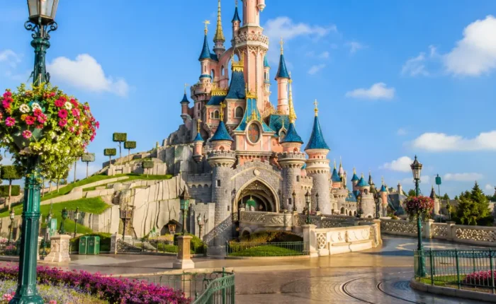 Disneyland Paris castle with fantasy gardens, clean pathways, blue sky, and bright morning family travel atmosphere