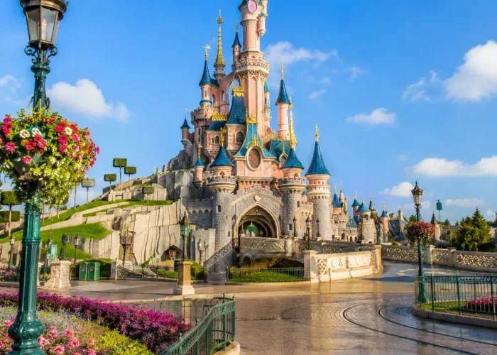 Disneyland Paris castle with fantasy gardens, clean pathways, blue sky, and bright morning family travel atmosphere