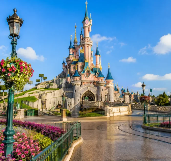 Disneyland Paris castle with fantasy gardens, clean pathways, blue sky, and bright morning family travel atmosphere