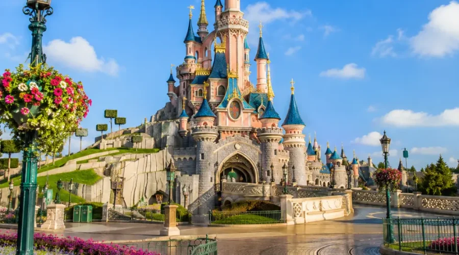 Disneyland Paris castle with fantasy gardens, clean pathways, blue sky, and bright morning family travel atmosphere