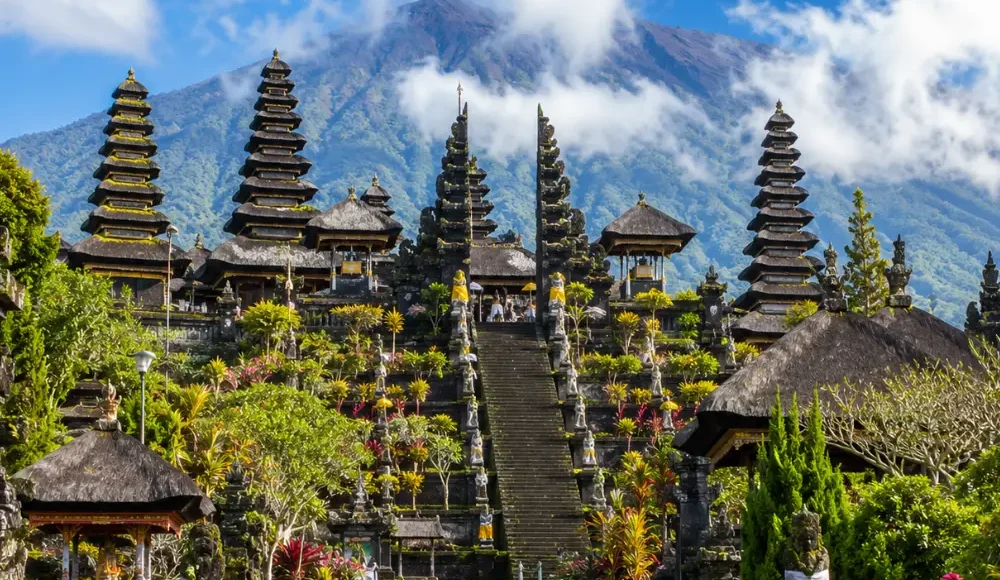 Besakih Temple Bali with Mount Agung views, traditional temple gates, lush greenery, and bright morning atmosphere.