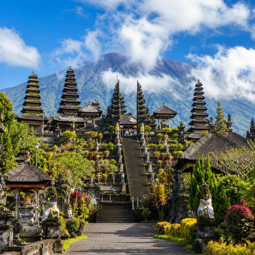 Besakih Temple Bali with Mount Agung views, traditional temple gates, lush greenery, and bright morning atmosphere.