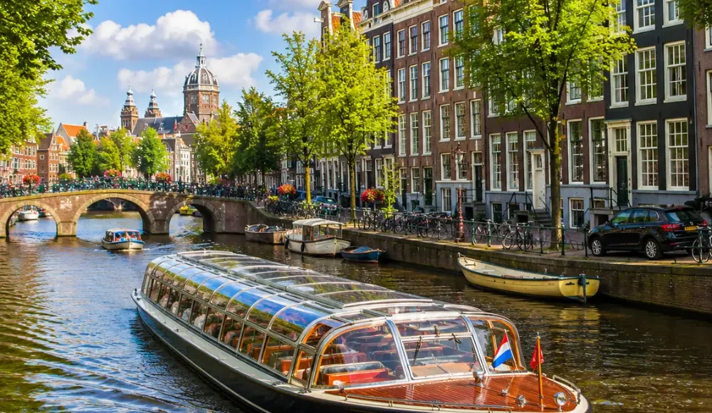 Amsterdam canal cruise with historic houses, arched bridges, calm waterways, and bright morning European atmosphere.