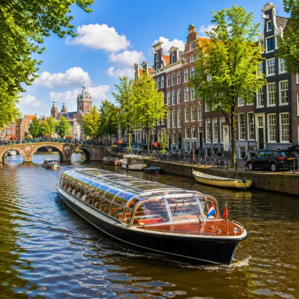 Amsterdam canal cruise with historic houses, arched bridges, calm waterways, and bright morning European atmosphere.
