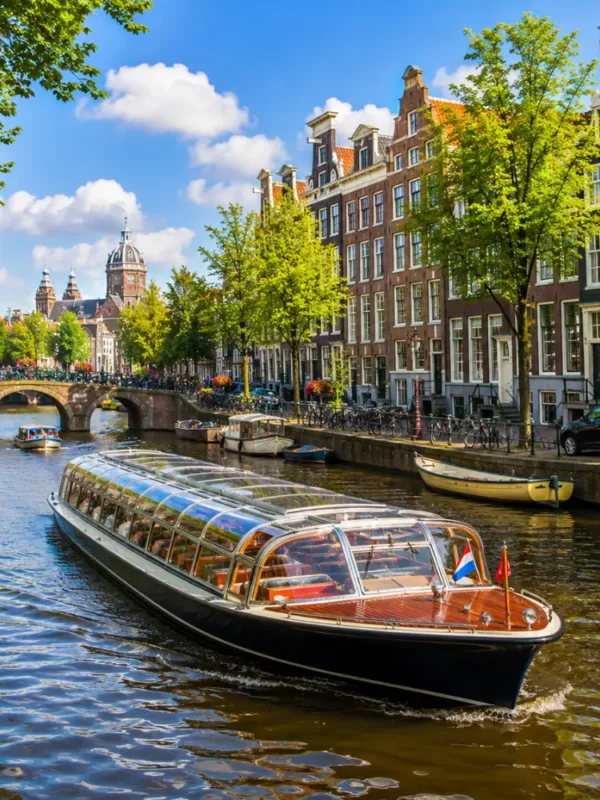 Amsterdam canal cruise with historic houses, arched bridges, calm waterways, and bright morning European atmosphere.