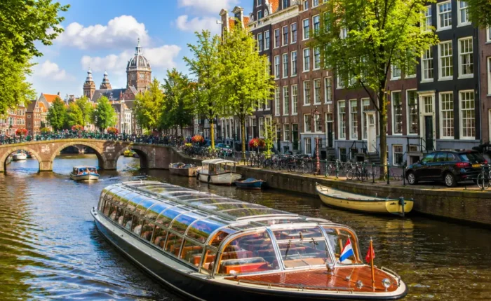 Amsterdam canal cruise with historic houses, arched bridges, calm waterways, and bright morning European atmosphere.