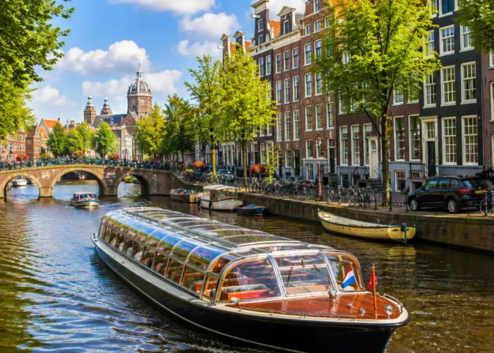 Amsterdam canal cruise with historic houses, arched bridges, calm waterways, and bright morning European atmosphere.