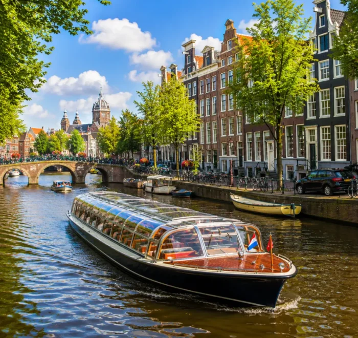Amsterdam canal cruise with historic houses, arched bridges, calm waterways, and bright morning European atmosphere.