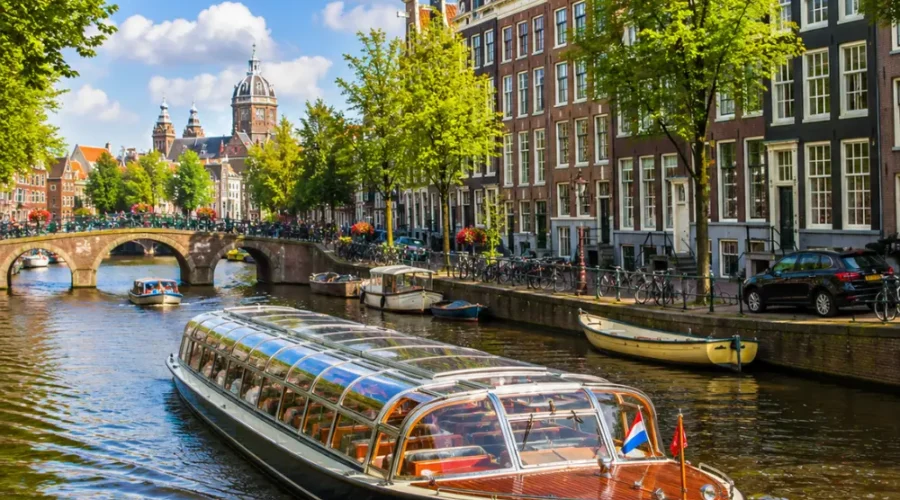 Amsterdam canal cruise with historic houses, arched bridges, calm waterways, and bright morning European atmosphere.
