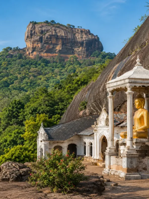 A breathtaking view of Sigiriya Rock Fortress rising dramatically above lush green forests alongside the ancient Dambulla Cave Temple with its golden Buddha statue, showcasing Sri Lanka's rich cultural heritage under a bright blue daytime sky.