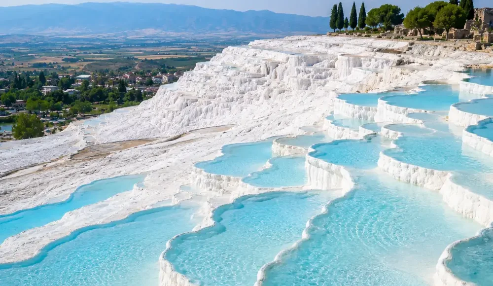 Pamukkale Turkey with white travertine terraces, turquoise thermal pools, ancient ruins, and bright morning atmosphere.