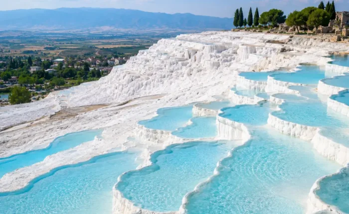 Pamukkale Turkey with white travertine terraces, turquoise thermal pools, ancient ruins, and bright morning atmosphere.