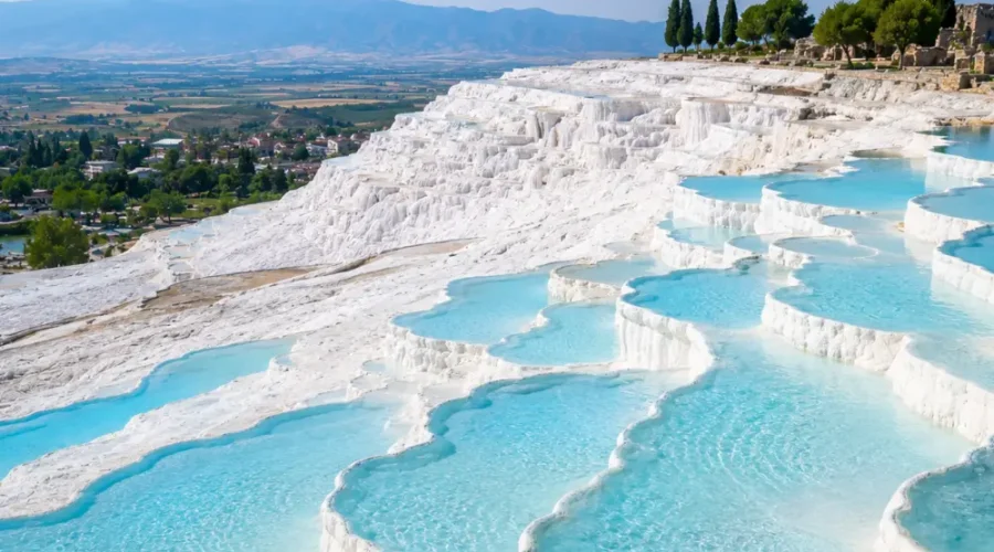Pamukkale Turkey with white travertine terraces, turquoise thermal pools, ancient ruins, and bright morning atmosphere.
