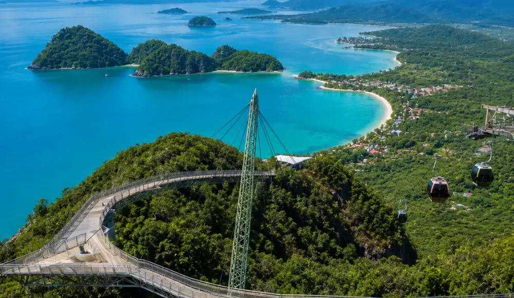 Crystal-clear tropical beach in Langkawi with turquoise water, limestone islands, luxury resort villas, and lush rainforest scenery.