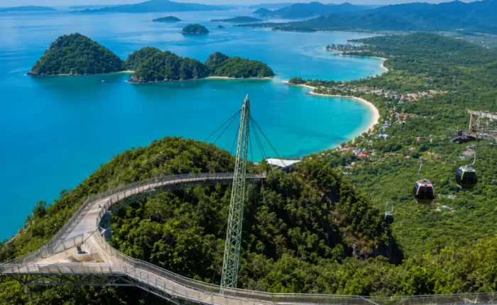 Crystal-clear tropical beach in Langkawi with turquoise water, limestone islands, luxury resort villas, and lush rainforest scenery.