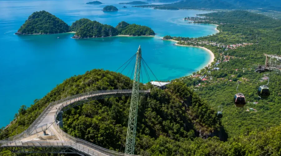 Crystal-clear tropical beach in Langkawi with turquoise water, limestone islands, luxury resort villas, and lush rainforest scenery.