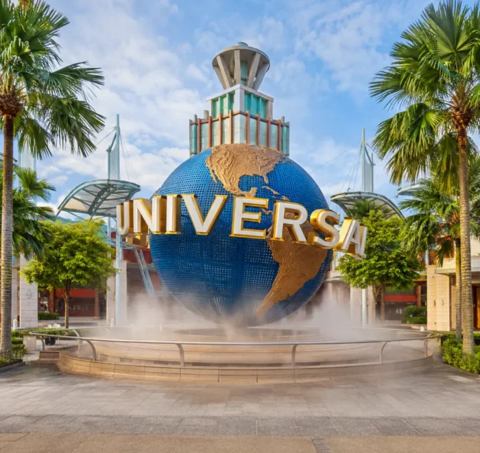 Universal Studios Singapore entrance with iconic globe, tropical palms, and bright morning travel atmosphere.