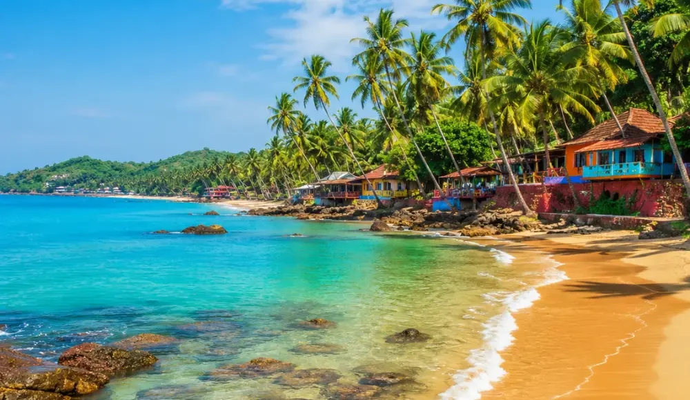 Goa beach with golden sand, blue sea, coconut palms and clear morning daylight for a tropical holiday escape.