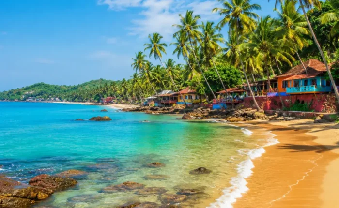 Goa beach with golden sand, blue sea, coconut palms and clear morning daylight for a tropical holiday escape.
