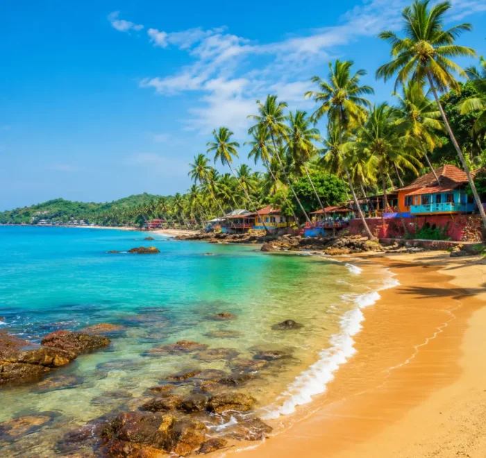 Goa beach with golden sand, blue sea, coconut palms and clear morning daylight for a tropical holiday escape.