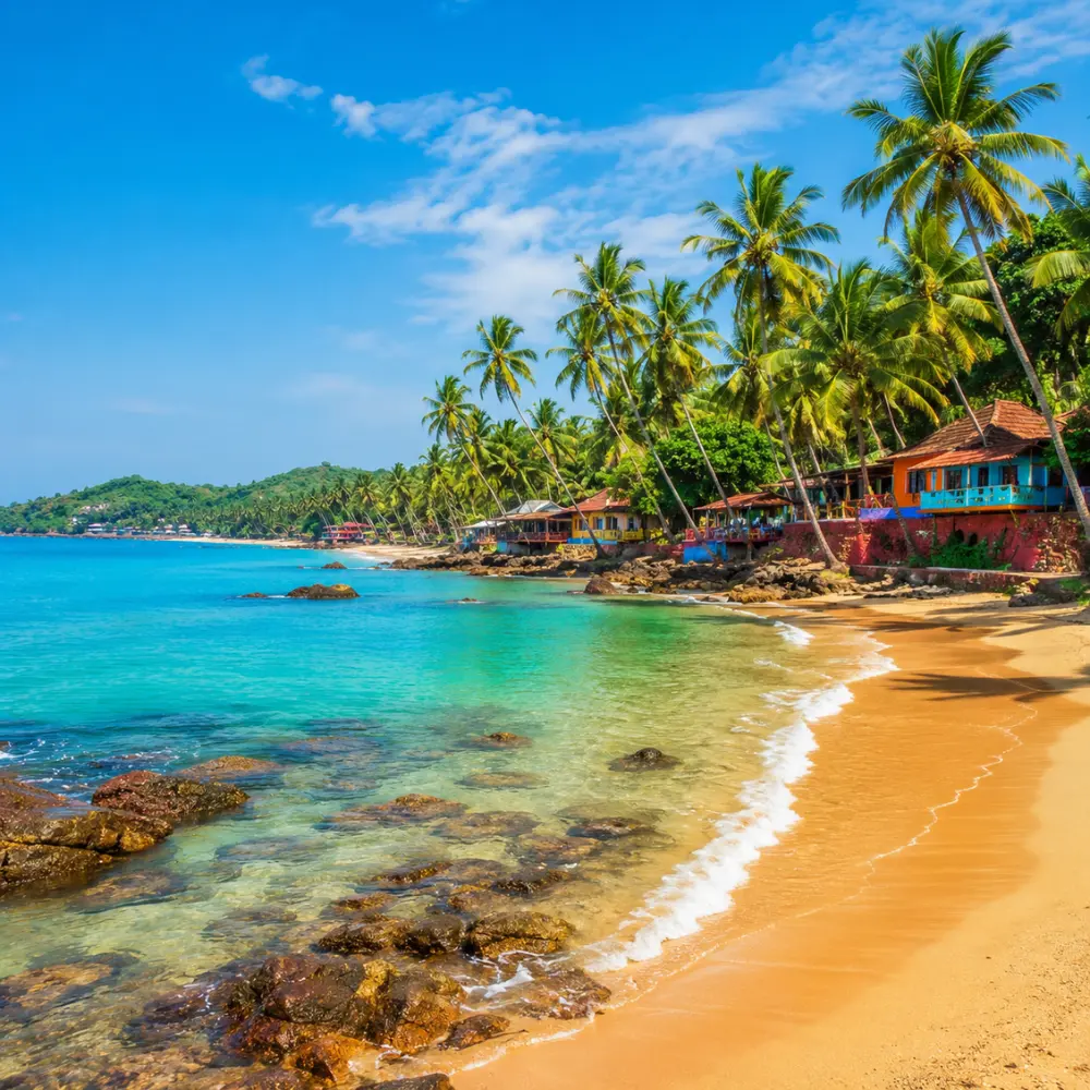 Goa beach with golden sand, blue sea, coconut palms and clear morning daylight for a tropical holiday escape.