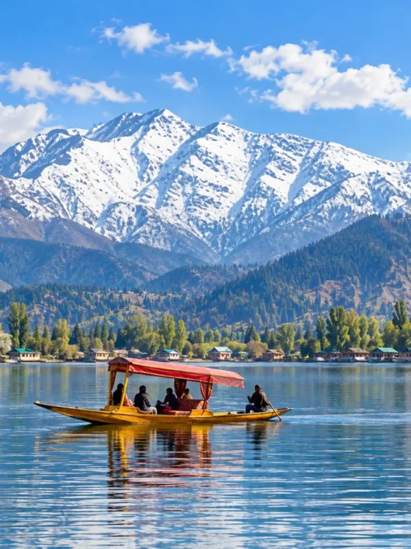 Shikara boat on Dal Lake in Srinagar, Kashmir, with snow-capped Himalayan mountains and scenic waterfront views