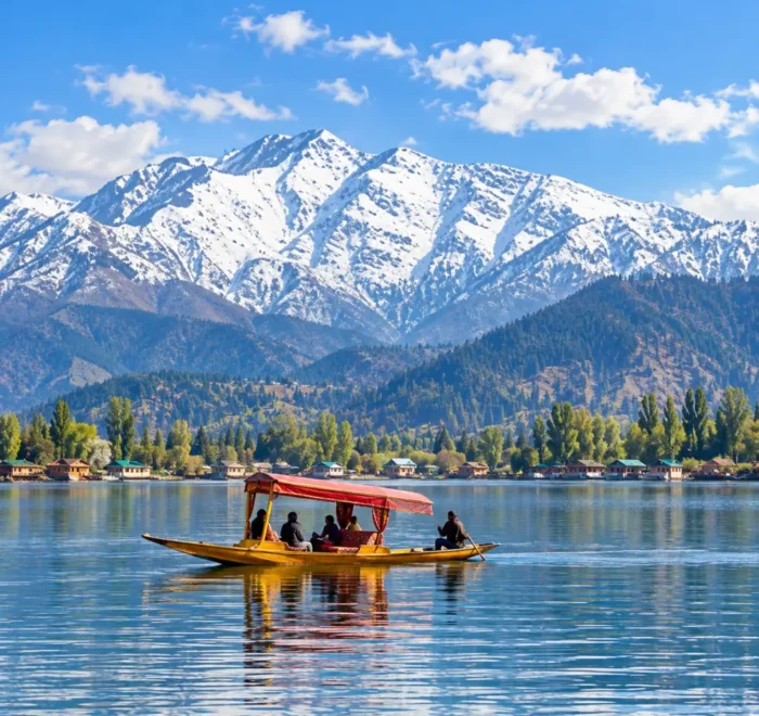 Shikara boat on Dal Lake in Srinagar, Kashmir, with snow-capped Himalayan mountains and scenic waterfront views